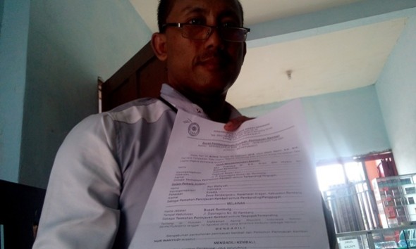 Nur Wahyudi menunjukkan salinan putusan PK dari MK saat berbincang dengan reporter mataairradio mengenai kemenangannya atas Bupati Rembang terhadap pemberhentiannya dari jabatan Kepala Desa Sendangwaru Kecamatan Kragan. (Foto: Pujianto)